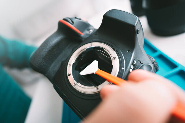 Крупный план фотографа с помощью сенсора для чистки камеры или мазка. Уход за фотооборудованием