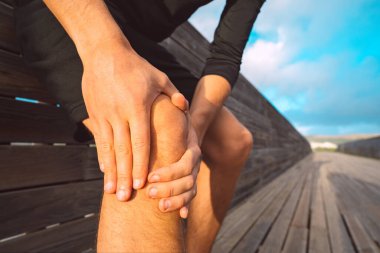 Diz ağrısından muzdarip bir adama yakın durun. Erkek koşucu yaralı olduğu için dizine masaj yapıyor. Koşarken ya da egzersiz yaparken yaralanmış..