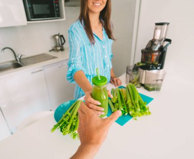 Taze kereviz detoks suyu. Sağlıklı bir kadın taze sıkılmış kereviz suyuyla ikram eder. Sağlıklı beslenme ve içme