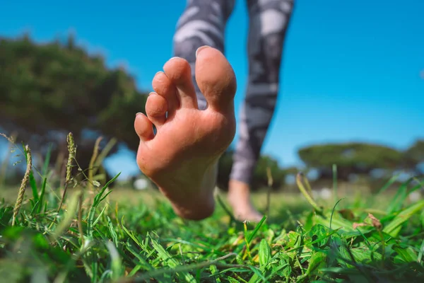 Mulher saudável andando descalça na grama verde no verão. Fechar os pés da mulher andando no chão e exercício — Fotografia de Stock