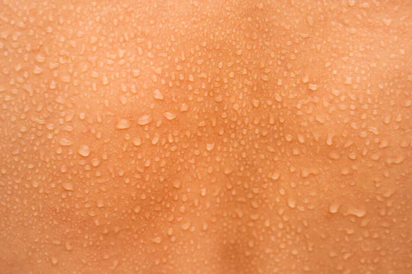 A água cai na pele traseira da mulher. Pele e suor humanos. Close up de pele molhada. — Fotografia de Stock