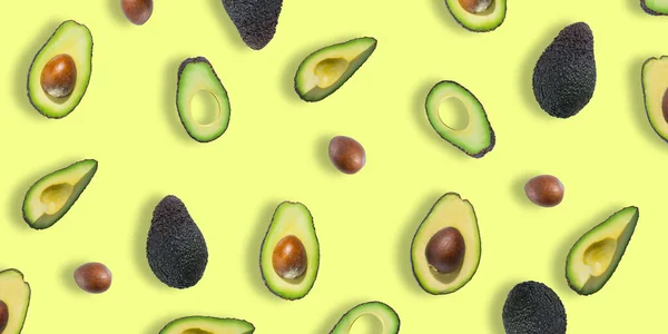 Pattern of fresh ripe green avocados. Avocado banner. Avocado pieces and halves isolated on a yellow background. Top view. Flat lay — Stock Photo, Image