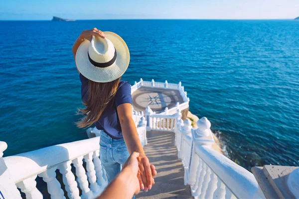 Giovane donna turistica spensierata in cappello bianco che porta il suo ragazzo alla vista sul mare. Seguitemi. Coppia in vacanza estiva. Viaggiare insieme. Balcon del Mediterraneo, Benidorm, Spagna — Foto Stock