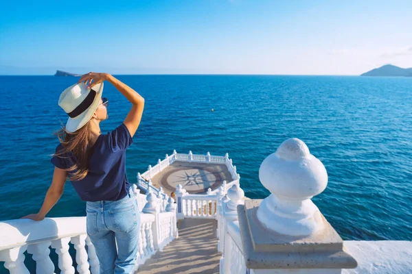 Giovane donna turistica spensierata con cappello da sole bianco che gode della vista sul mare o sull'oceano a Balcon del Mediterraneo, Benidorm, Spagna. Vacanze estive. — Foto Stock