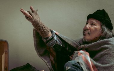 Evsiz bir adam, yoldan geçen birinden yüz maskesi alır çünkü işsiz ve açtır. Covid 19 salgınından dolayı kaldırımda yaşıyor..