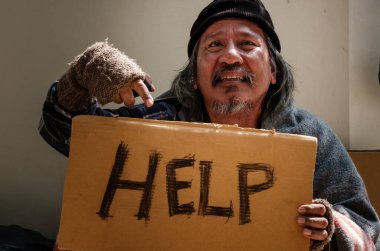 Evsiz bir adam, yoldan geçen birinden yüz maskesi alır çünkü işsiz ve açtır. Covid 19 salgınından dolayı kaldırımda yaşıyor..