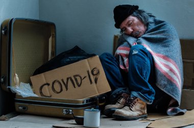 Evsiz bir adam yardım beklerken yorgun ve bitkin. Covid 19 salgınından dolayı kaldırımda yaşıyor..