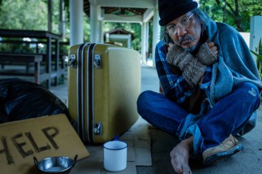 Evsiz bir adam, yoldan geçen birinden yüz maskesi alır çünkü işsiz ve açtır. Covid 19 salgınından dolayı kaldırımda yaşıyor..