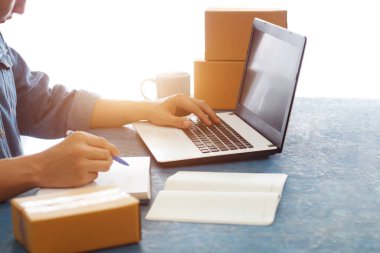 Masalarında çalışan Asyalı erkekler not defterleriyle çevrimiçi müşterilerden, çevrimiçi iş ve e-ticaretten, çevrimiçi ürünler satan mağazalardan gelen emirleri kabul ediyorlar..