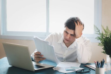Genç Asyalı erkekler iş yerinde strese girerler. Harcama faturasına bakarken, diğer yandan da kredi kartı borçlarını ve tüm faturaları ödemek için para bulmayı düşünüyorum. Finansal sorunları kabul et.