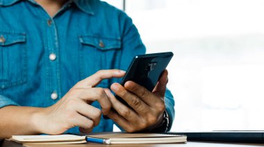 Genç adam akıllı telefon kullanıyor, internet üzerinden satış yapıyor, internet üzerinden iş yapıyor..