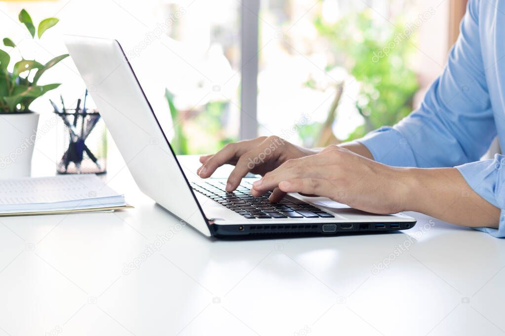 The hand of the office manager uses a laptop keyboard while working.