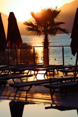 Denizde gün doğumu, arka planda dağlara karşı