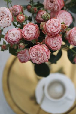 Altın tepside bir fincan kahve ve bir buket pembe gül