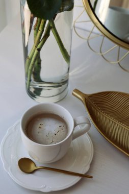 Altın tepside bir fincan kahve ve bir buket pembe gül