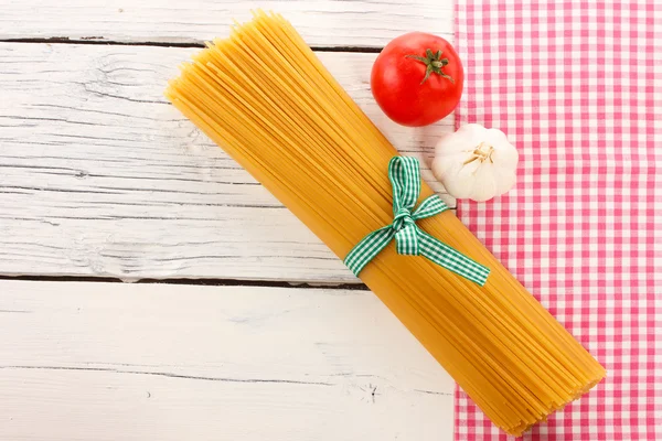 Damalı masa örtüsü, domates, sarımsak ve beyaz tahta üzerinde spagetti — Stok fotoğraf