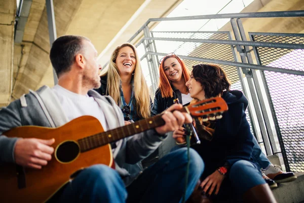 Feliz grupo de amigos disfrutando tocando la guitarra y cantando toge — Foto de Stock