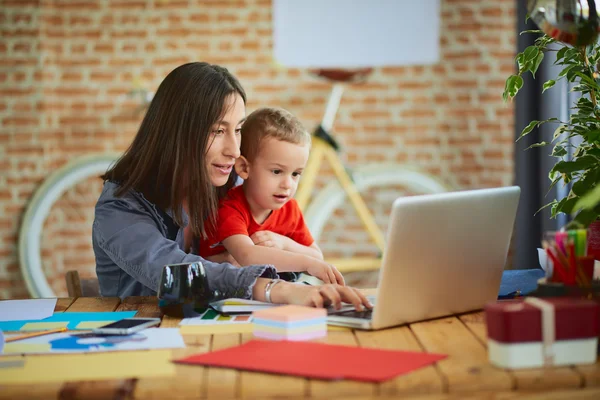 Woman working in office, son helping her — Stock Photo, Image