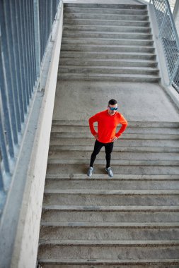 Orta yaşlı sporcunun hava manzarası merdivenlerde ayakta duran, elleri kalçasında. Mola verdi..