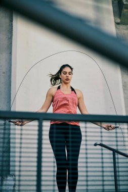 Sporcu kadın ipten atlıyor ve şehir dışında kardiyo egzersizleri yapıyor..