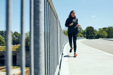 Köprüde koşan sağlıklı bir kadın koşucu..