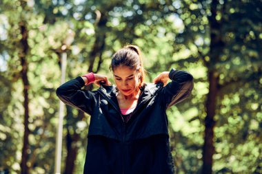 Formda sporcu kadın, doğada dururken kapüşonlu giyer..