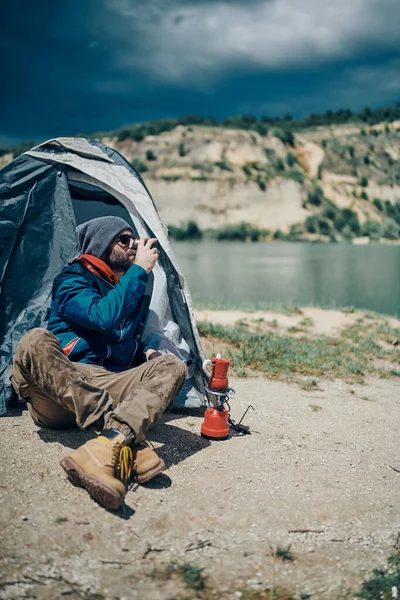 Ένας Εξερευνητής Κάθεται Στη Σκηνή Στη Λίμνη Κοιτάζοντας Νερό Και — Φωτογραφία Αρχείου