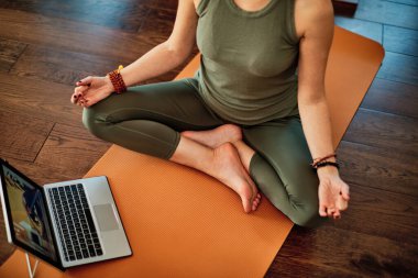 Evde video öğretmeniyle yoga yapan bir kadın..