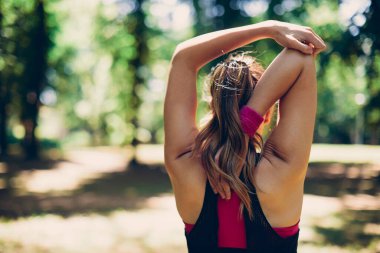 Formda koşucunun doğada ısınma egzersizleri yaptığı arka görünüm.