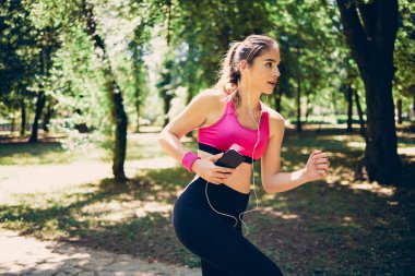 Güneşli bir günde doğada koşan hızlı sporcu kadın..