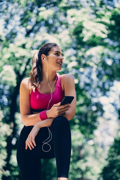 Gülümseyen Sporcu Kadının Doğada Koşmaya Ara Verip Telefon Kullanmasının Düşük — Stok fotoğraf