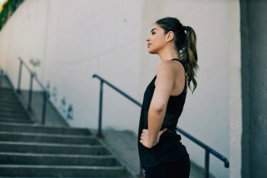 Genç ve çekici beyaz kadın dışarıda duruyor ve koşuya ara veriyor..