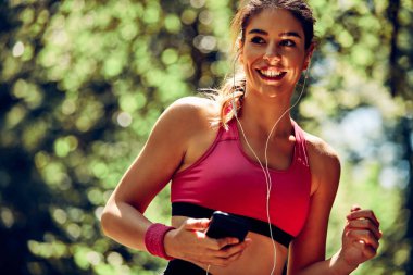 Ormanda koşup müzik dinleyen çekici bir bayan koşucu..