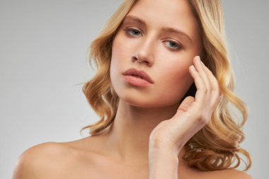 Makyajsız sevimli sarışın, temiz ve kıvırcık saçlı stüdyoda poz veriyor..