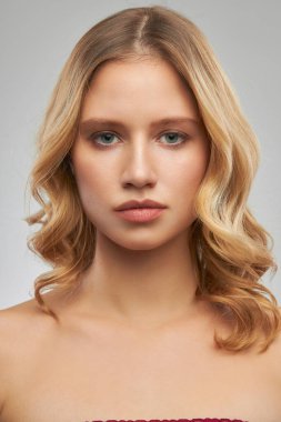 Makyajsız sevimli sarışın, temiz ve kıvırcık saçlı stüdyoda poz veriyor..
