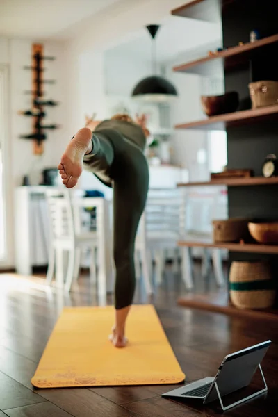 Woman practicing yoga at home with video tutorial.