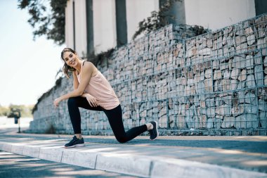 Sporcu kadın şehir dışında koşmak için esniyor ve hazırlanıyor.