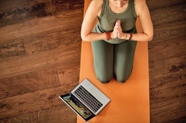 Evde video öğretmeniyle yoga yapan bir kadın..