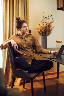 Hamile kadın evde oturuyor ve dizüstü bilgisayar kullanıyor..