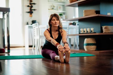 Orta yaşlı Yogi kadın evde yoga yapıyor.