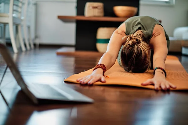 Woman practicing yoga at home with video tutorial.