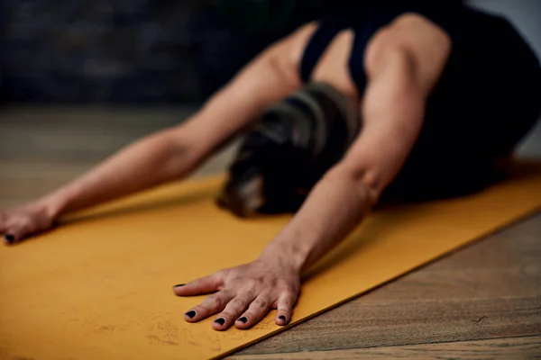 Close up of woman in child\'s yoga pose. Selective focus on hand
