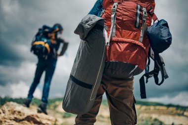 Kamp yapan bir adam ayakta durup doğaya bakıyor. Sırtında sırt çantası var..