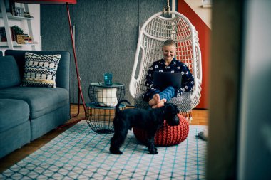 Sırıtkan, kısa saçlı, kucağında dizüstü bilgisayarla oturan ve rahatlayan son sınıf öğrencisi bir kadın..