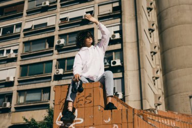 Kıvırcık saçlı güzel bir kız şehrin kenar mahallelerinde oturuyor ve güneşli bir günün tadını çıkarıyor..