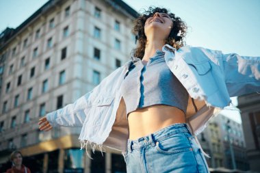 Kıvırcık saçlı, sokaklarda dans eden ve müzik dinleyen genç mutlu kız..