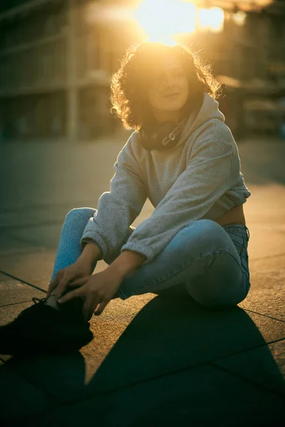 Ein Junges Glückliches Mädchen Sitzt Mit Kopfhörern Auf Dem Bürgersteig — Stockfoto