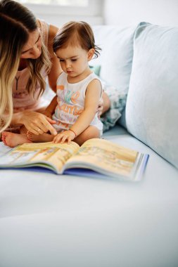Genç bir anne küçük kızına okumayı öğretiyor..