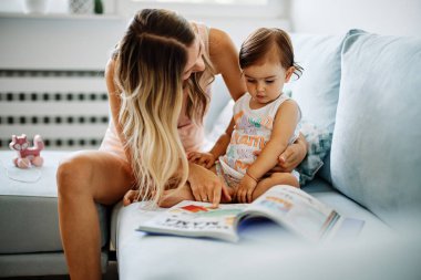 Genç bir anne küçük kızına okumayı öğretiyor..