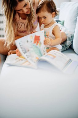 Genç bir anne küçük kızına okumayı öğretiyor..